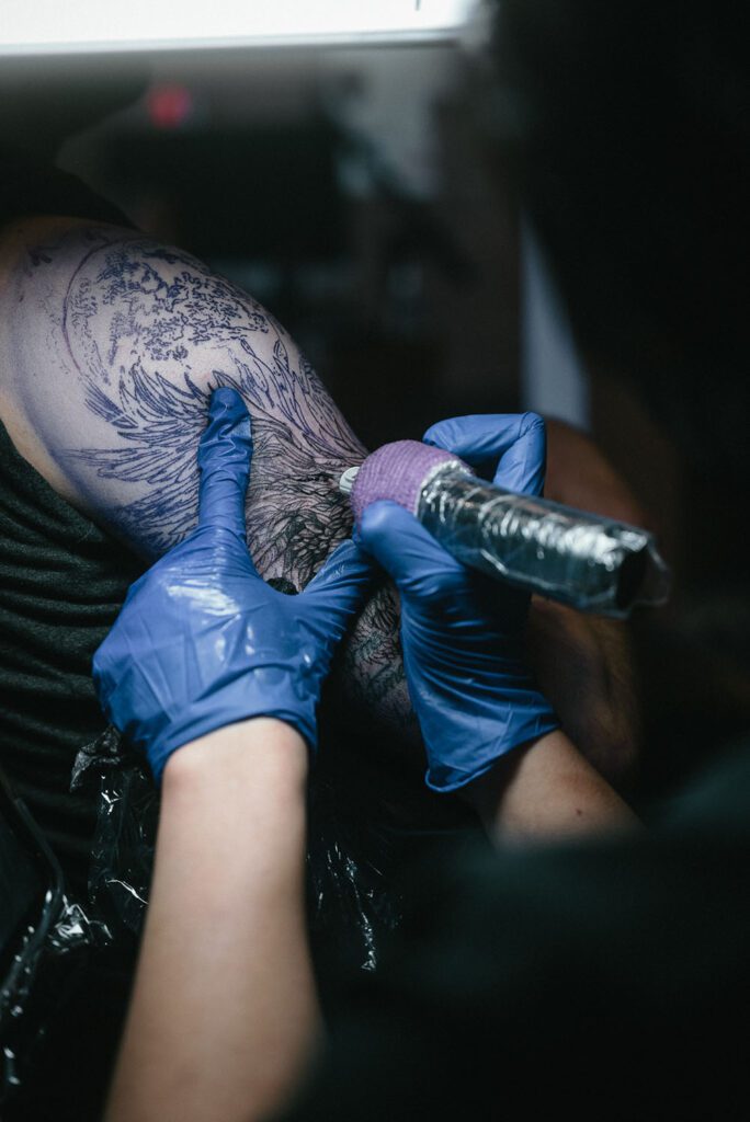 Prepare tattoo shop Markham. Stabby'zz tattoo artist stretching skin and applying tattoo machine needle to tattooed skin